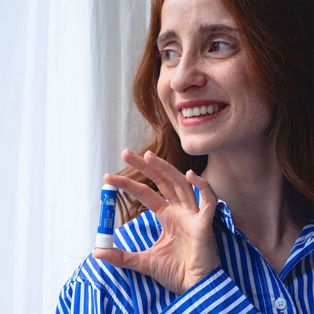 Femme avec inhalateur. Elle le tient à la main. Chemise rayée bleu et blanc.