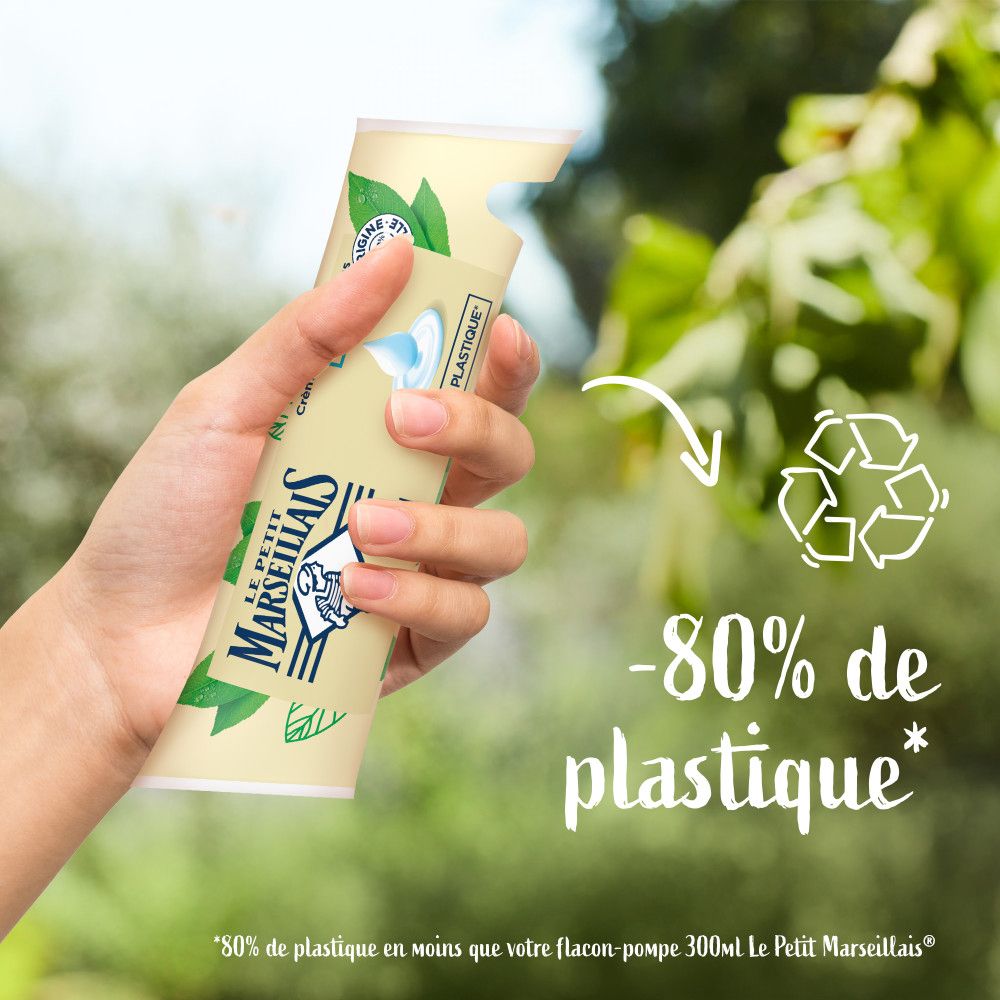Main tenant un sachet de Crème lavante Mains Lait. Symbole de recyclage. Texte: -80% de plastique.