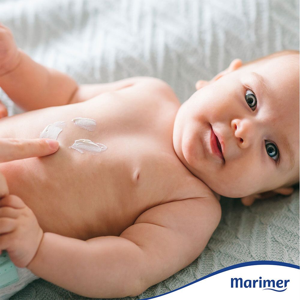 Bébé couché sur le dos, poitrine enduite de crème. Logo Marimer en bas à droite.