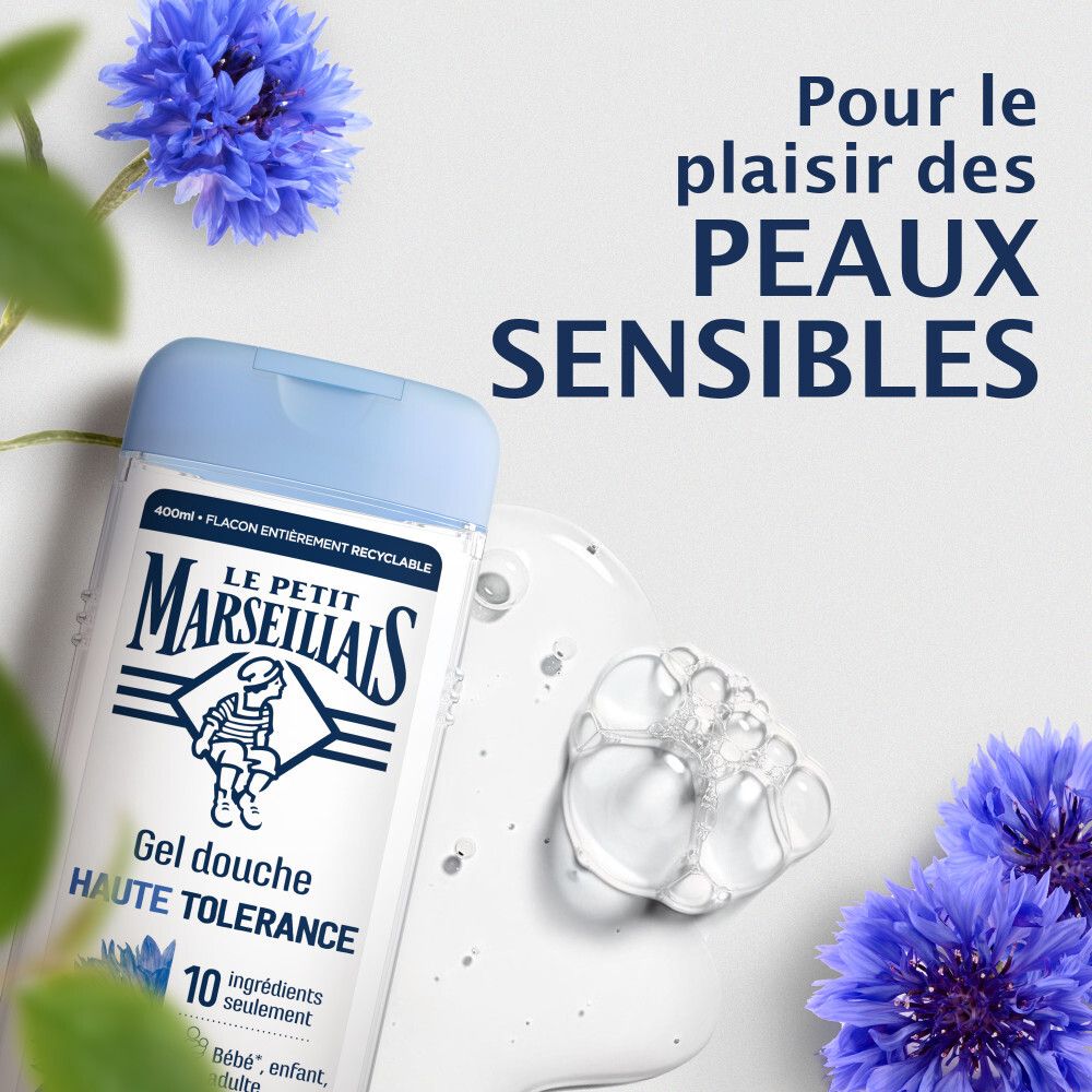 Flacon de gel douche près de mousse et de bleuets. Pour peaux sensibles.