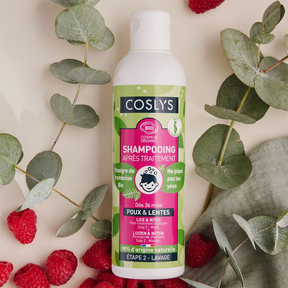 Flacon blanc avec étiquette verte et rose. Coslys Shampooing Après-Traitement. Vinaigre de framboise bio. Certifié bio. Entouré de framboises et feuilles.