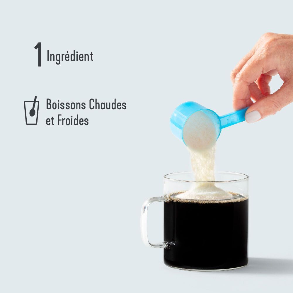 Une main verse de la poudre de collagène d'une cuillère bleue dans une tasse de café.