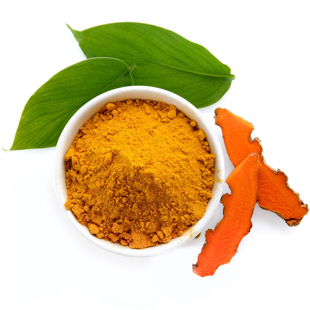 Bol blanc avec poudre de curcuma, feuilles vertes et morceaux de curcuma. Sur fond blanc.