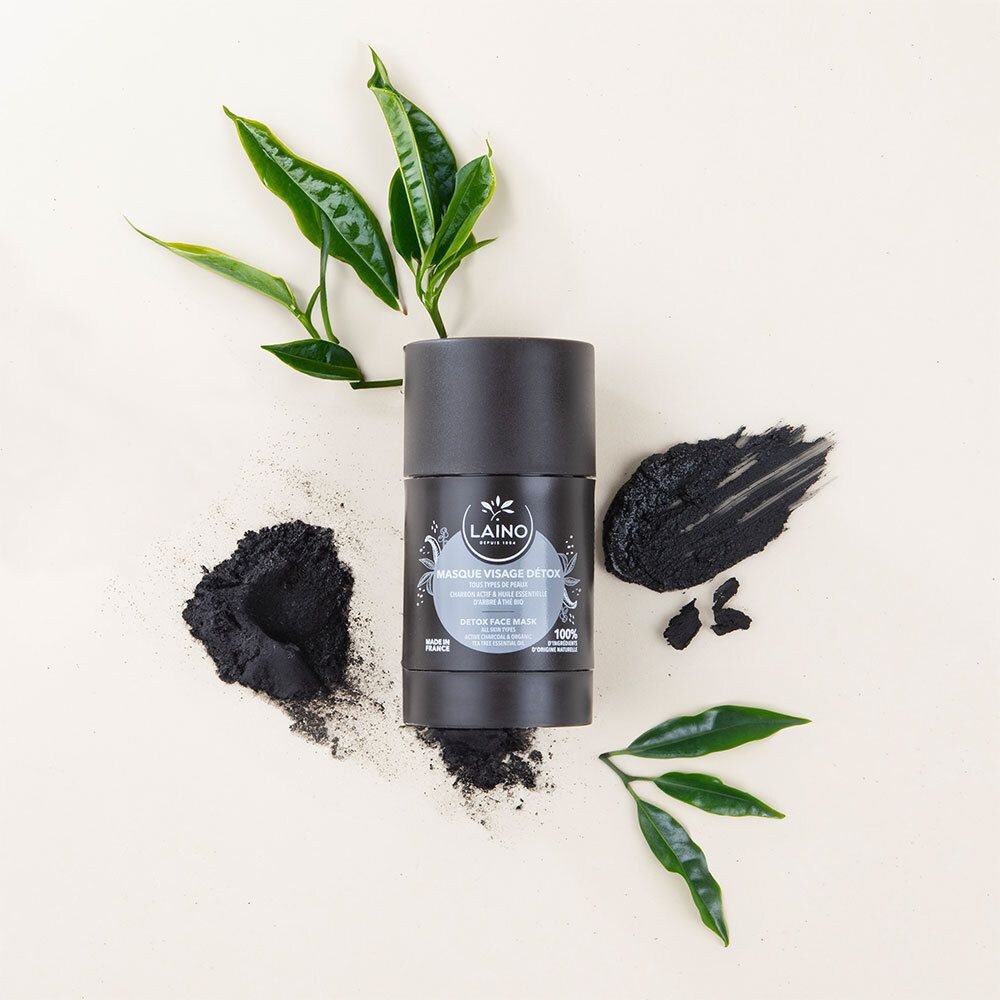 Masque facial noir et plantes sur fond clair. Le masque est dans un emballage cylindrique.