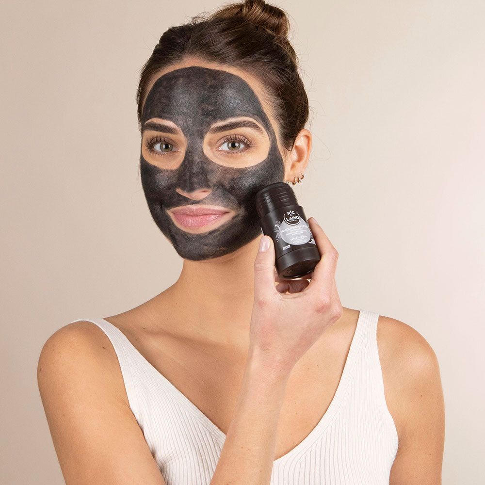 Femme avec un masque facial noir. Elle tient un emballage cylindrique noir dans sa main.