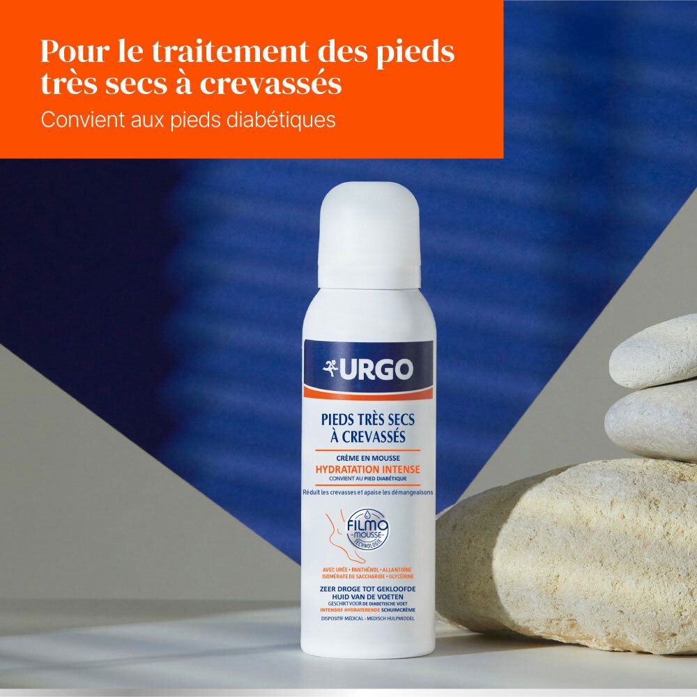 Flacon blanc Urgo. Crème en mousse pour pieds très secs à crevasses. Texte en français. Fond bleu et pierre.