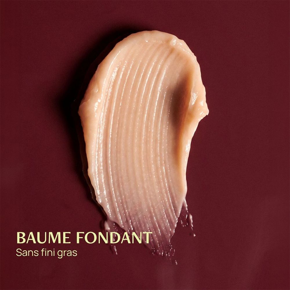 Une texture crémeuse, beige clair, striée, posée sur un fond bordeaux. "BAUME FONDANT Sans fini gras".
