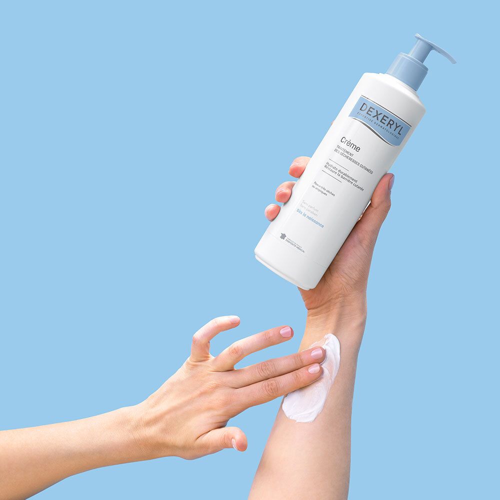 Une main applique la crème Dexeryl sur un avant-bras.