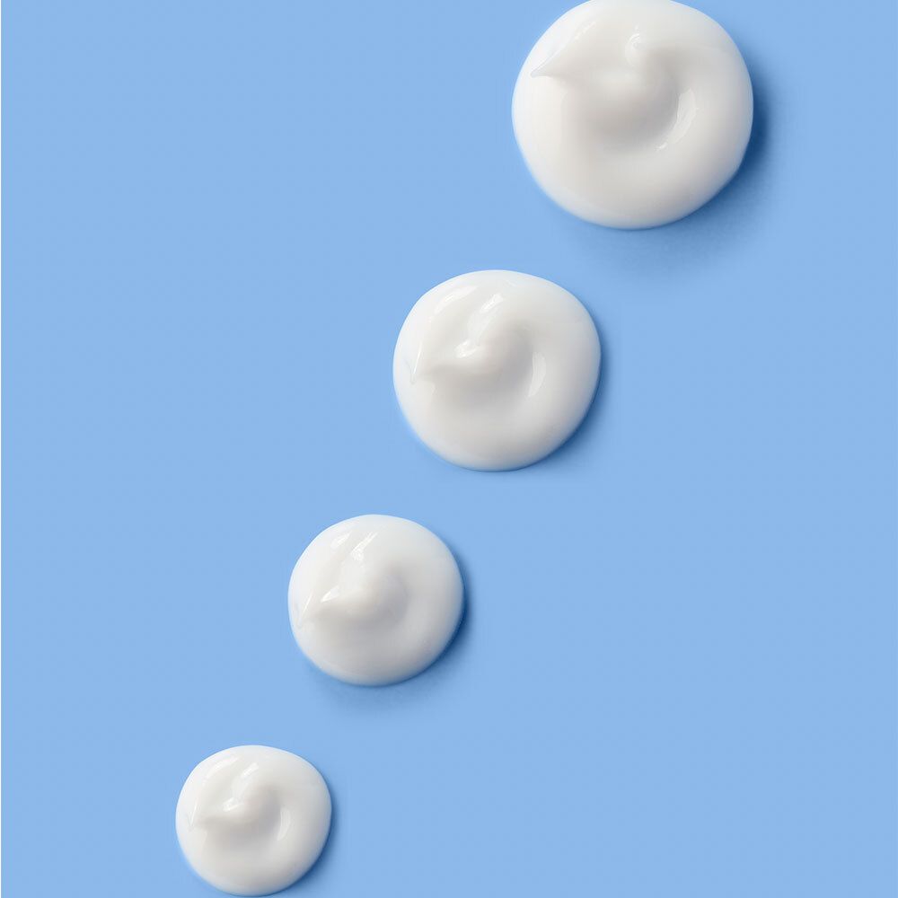 Quatre points de crème Dexeryl sur fond bleu.