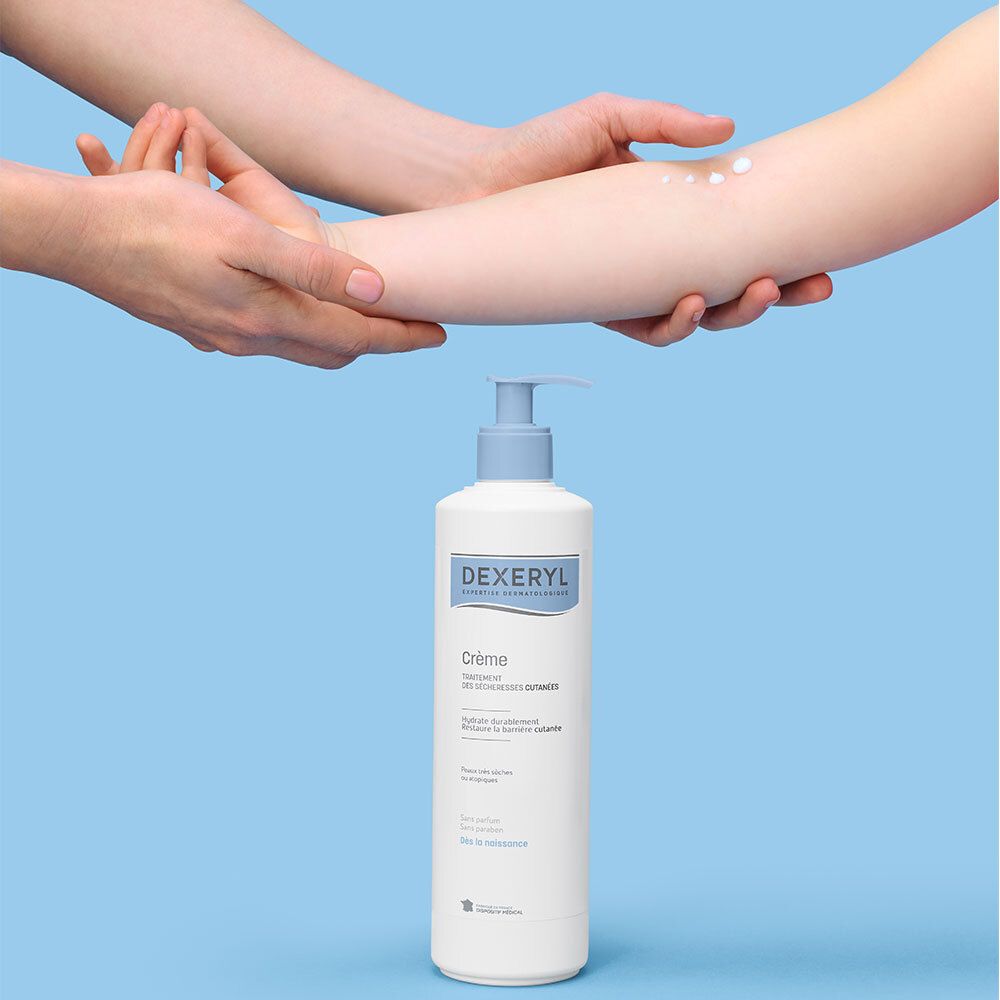Une main applique la crème Dexeryl sur un avant-bras, la bouteille est à côté.