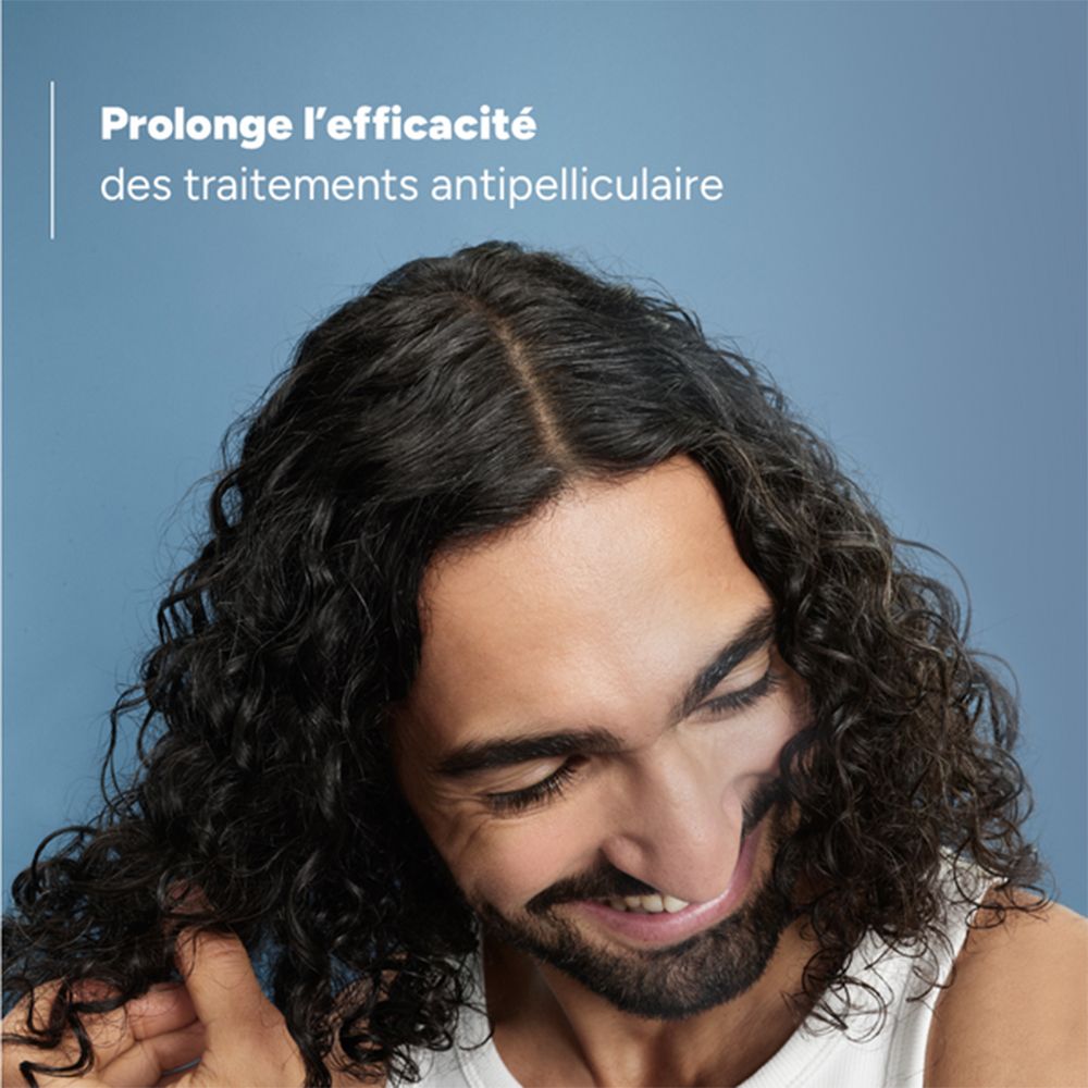 Homme aux cheveux bouclés. Inscription: Prolonge l'efficacité des traitements antipelliculaires.