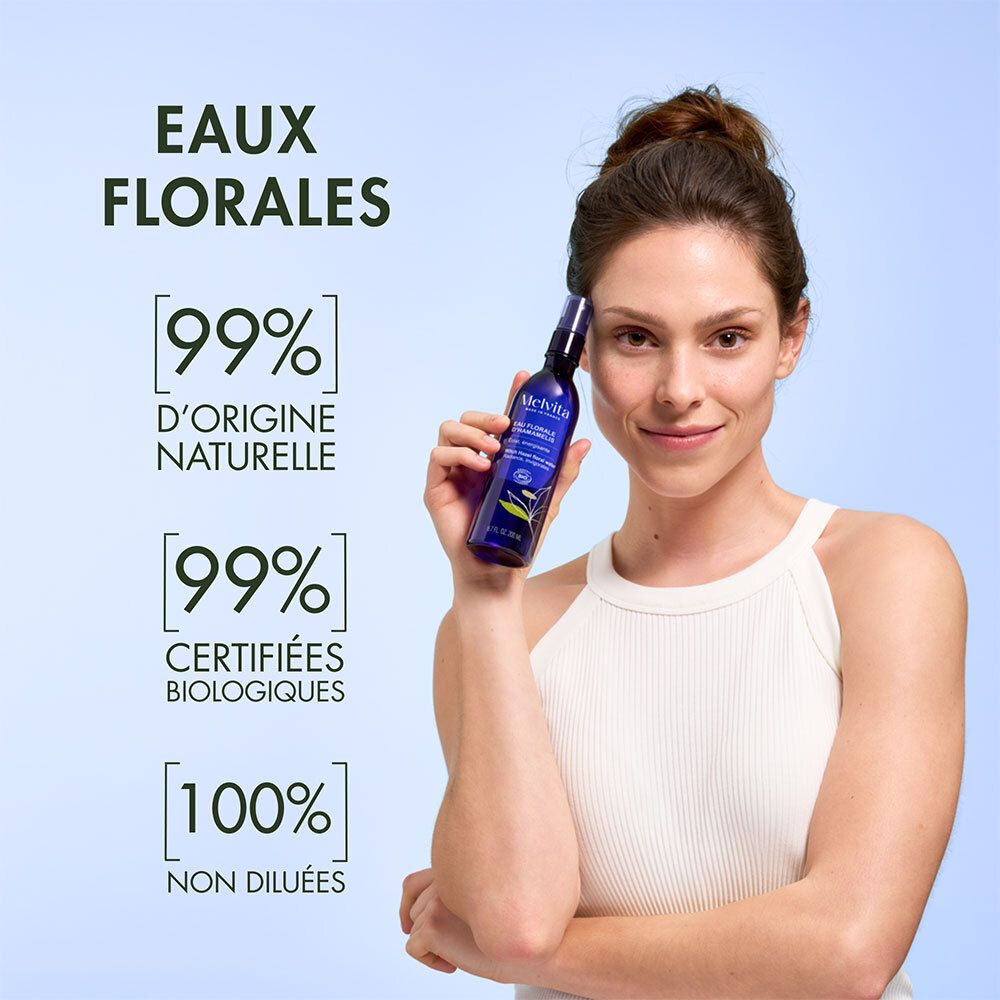 Femme tenant un flacon Melvita Eau Florale de Bleuet. Texte: 99% naturel, 99% certifié bio, 100% non dilué.