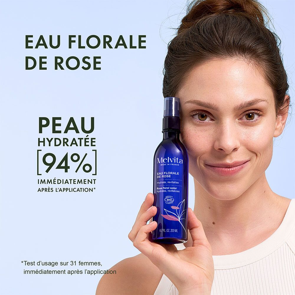 Femme tenant une bouteille d'eau florale de rose Melvita, peau hydratée à 94%.