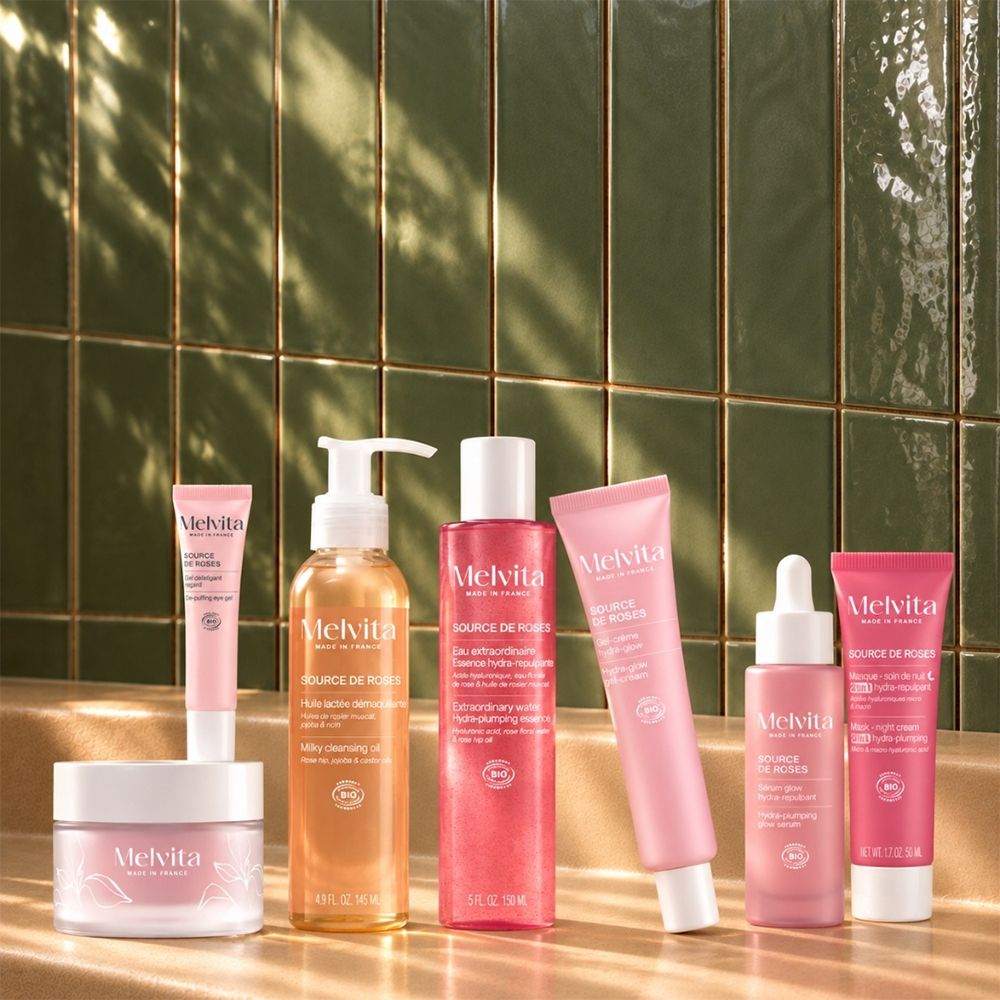 Une gamme de produits de soins de la peau Melvita dans des bouteilles et des pots roses et oranges.