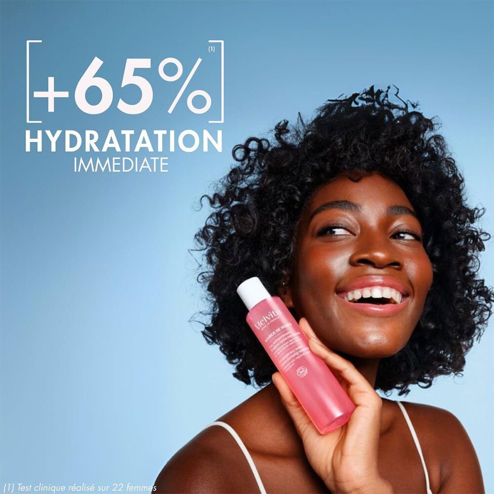 Femme tenant un flacon d'essence de rose. Texte: +65% Hydratation immédiate.