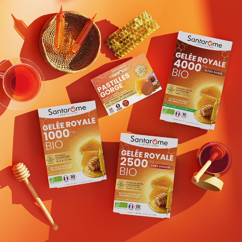 Plusieurs boîtes Santarome Gelée Royale Bio, Pastilles Gorge, cuillère à miel, tasse de thé et nid d'abeilles.