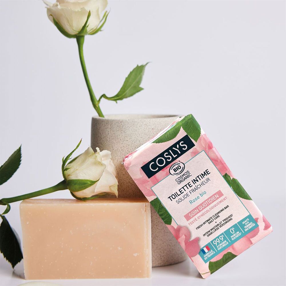 Produit et emballage. Savon rose à côté de l'emballage. Emballage avec logo et nom du produit. Roses et vase en arrière-plan.