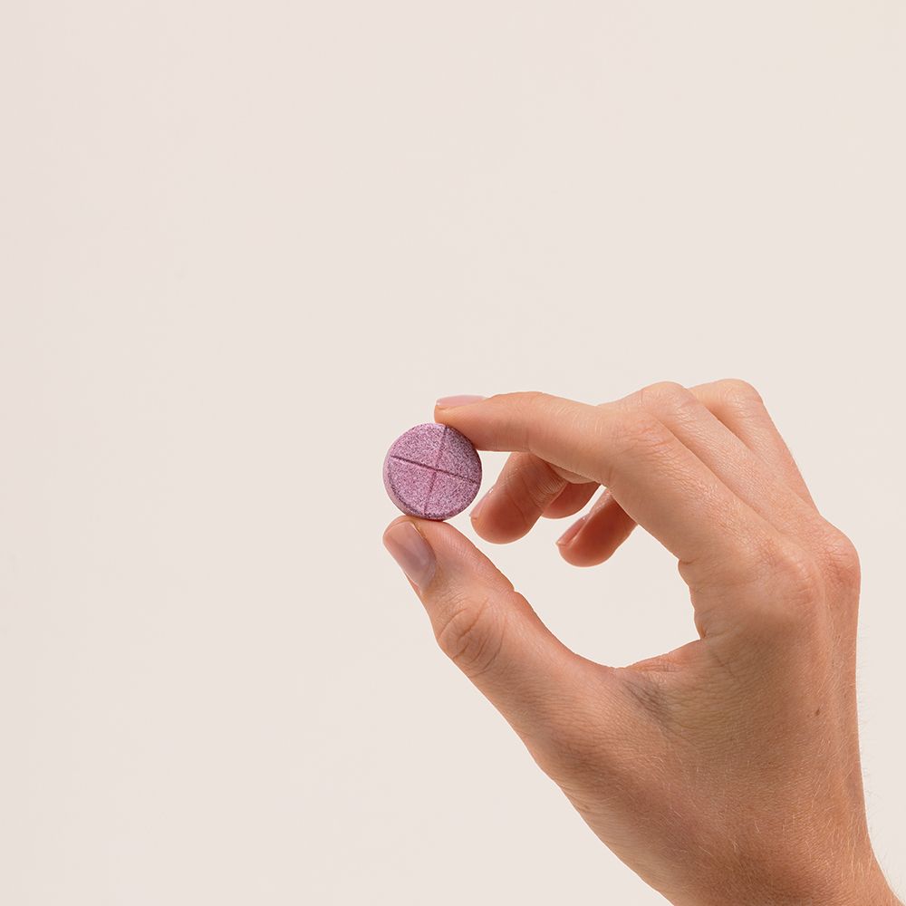 Main tenant un comprimé rose. Lignes croisées sur la surface.