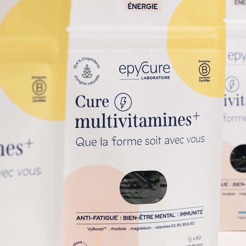 Gros plan sur des sachets Cure multivitamines+. Inscription: epycure, certification B. Plusieurs sachets en arrière-plan.