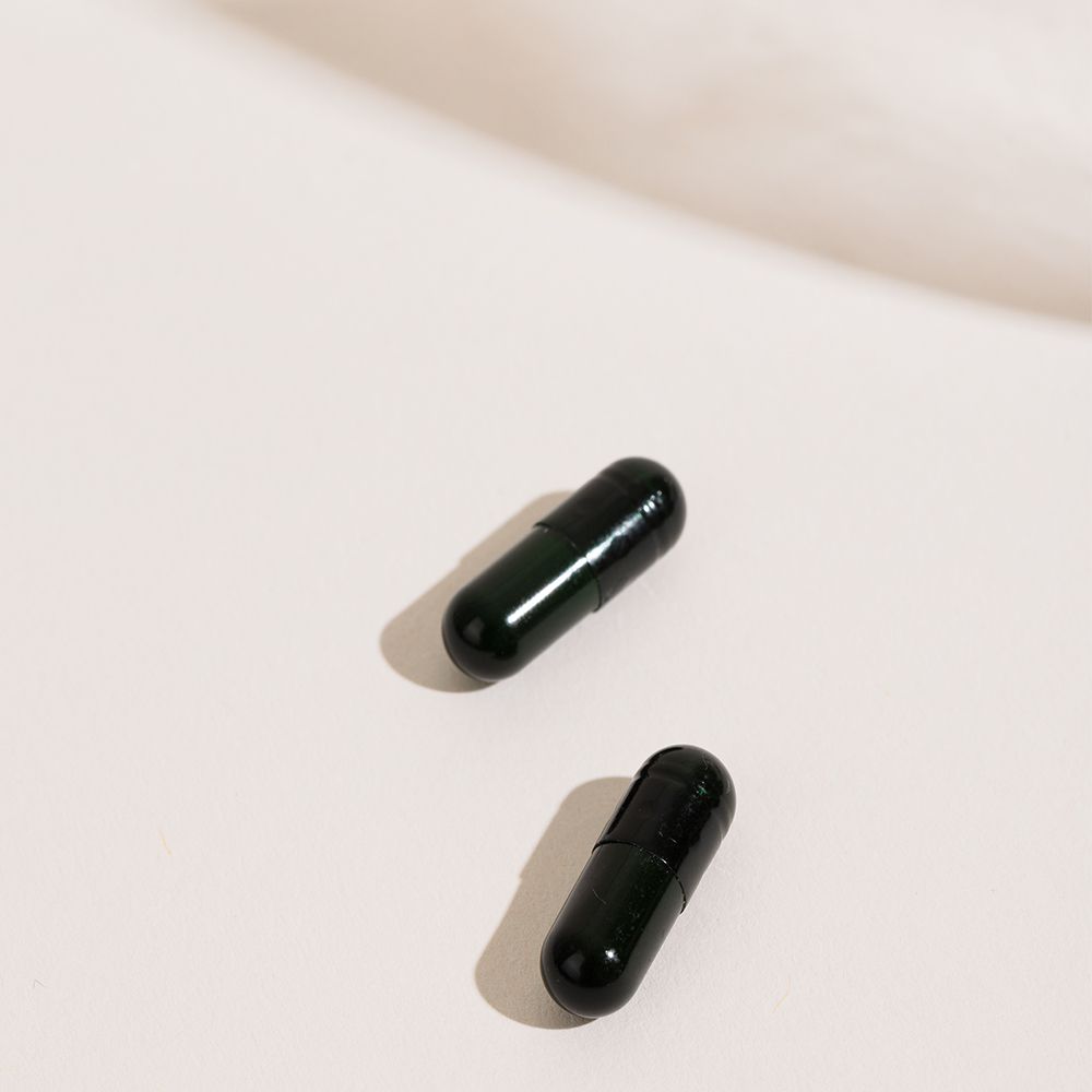 Deux gélules noires sur fond blanc. Ombres.