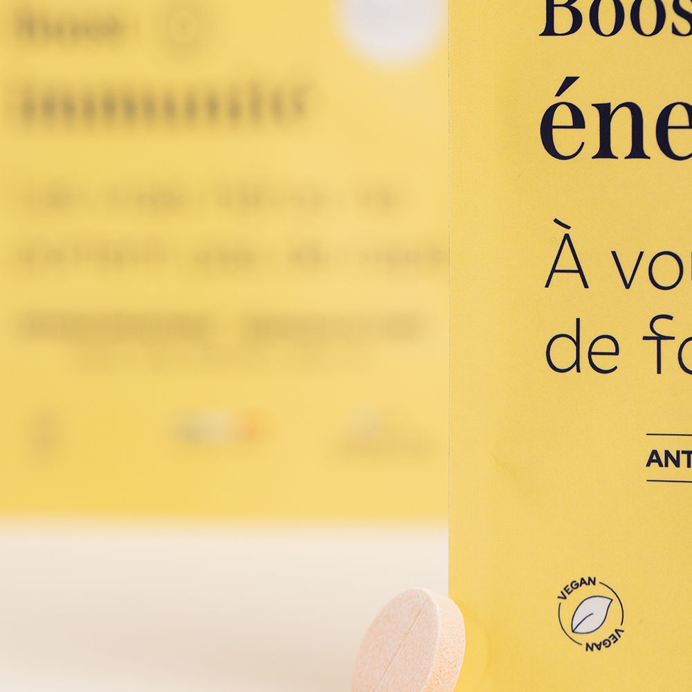 Gros plan sur un comprimé. Forme ronde, couleur rose, avec une rainure.