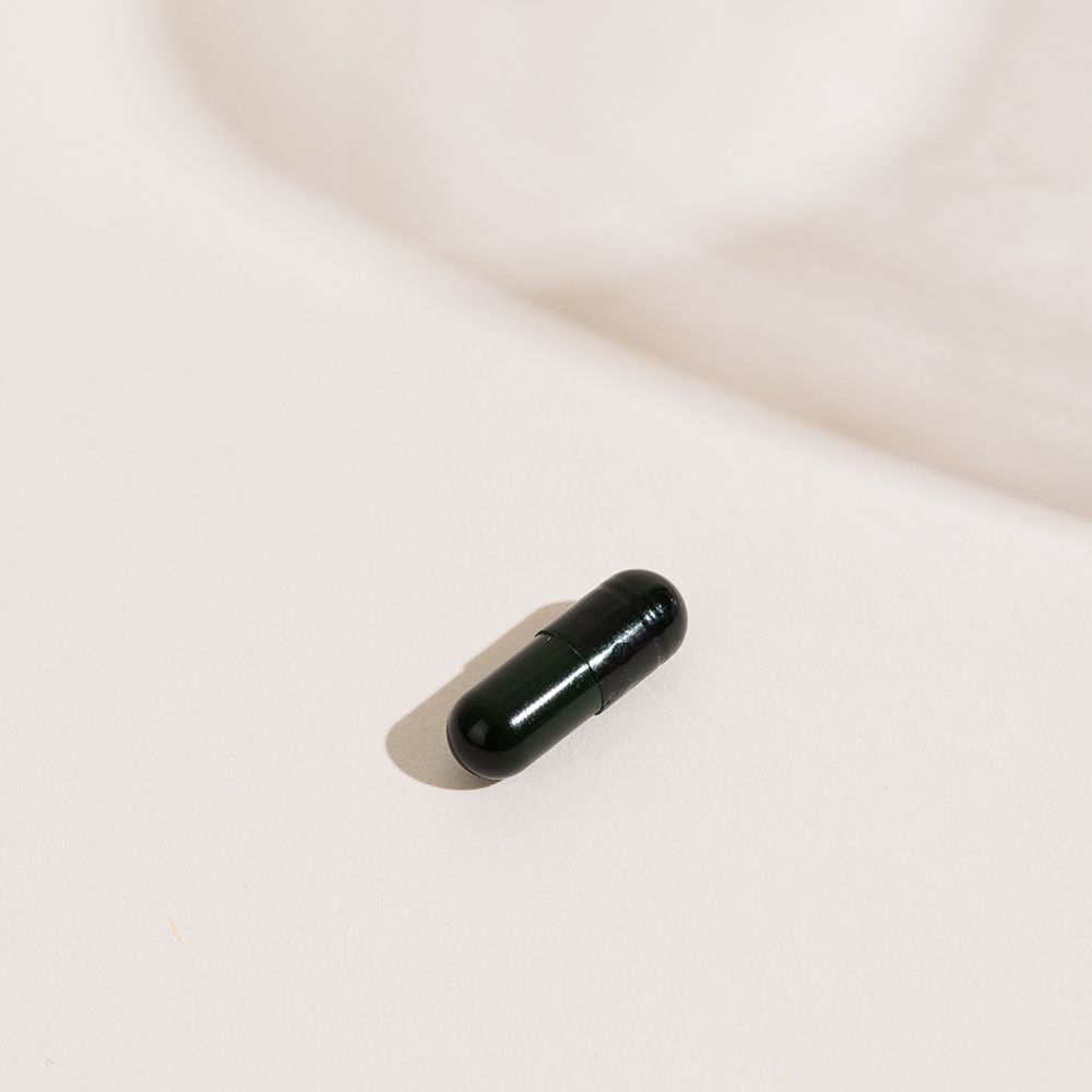 Une gélule verte sur fond clair.