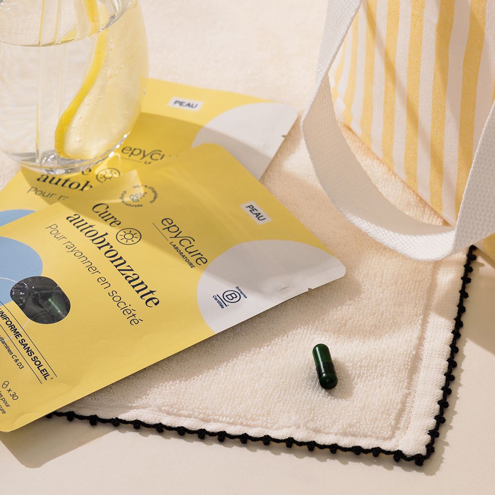 Deux sachets jaunes, gélule, verre d'eau, serviette. Inscription: Cure autobronzante.