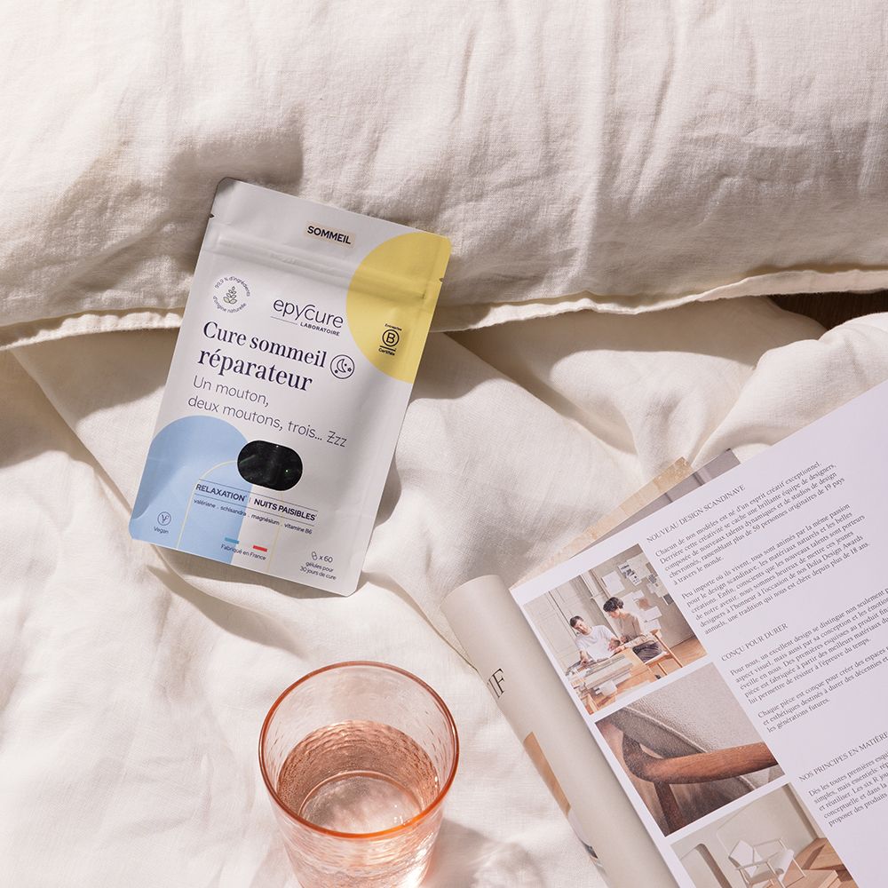 Emballage, verre et magazine sur linge de lit. Inscription: Cure sommeil réparateur. Marque: epycure. Emballage jaune et blanc.