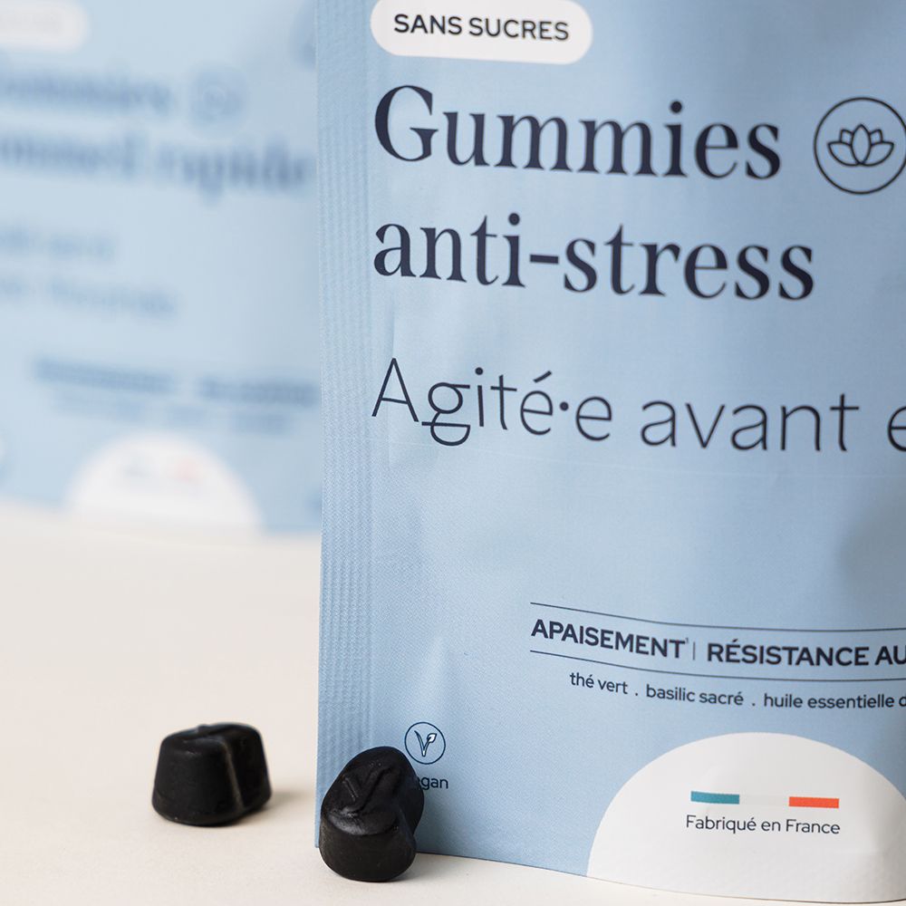 Gros plan sur deux gummies noirs à côté d'un sachet. Inscription: Gummies anti-stress sans sucres.