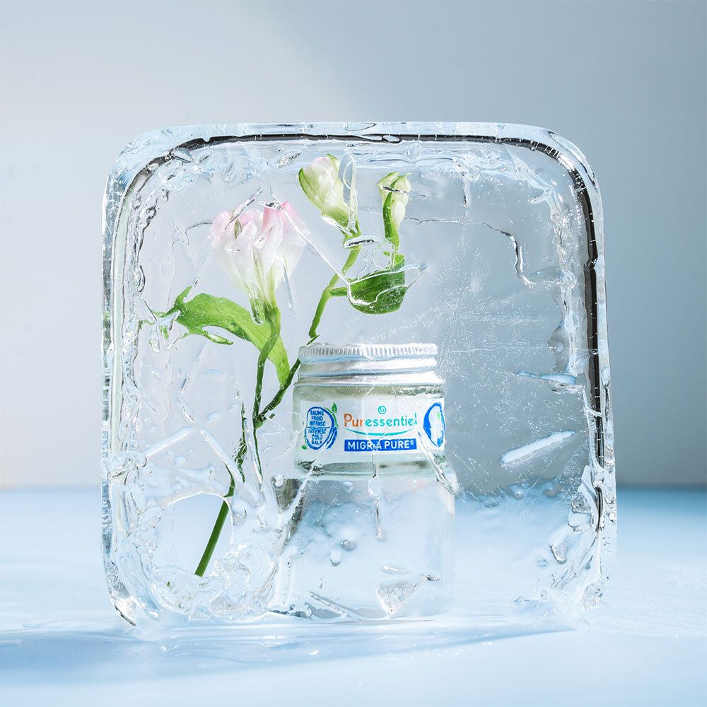 Pot Puressentiel Migra Pure dans un bloc de glace avec une fleur.