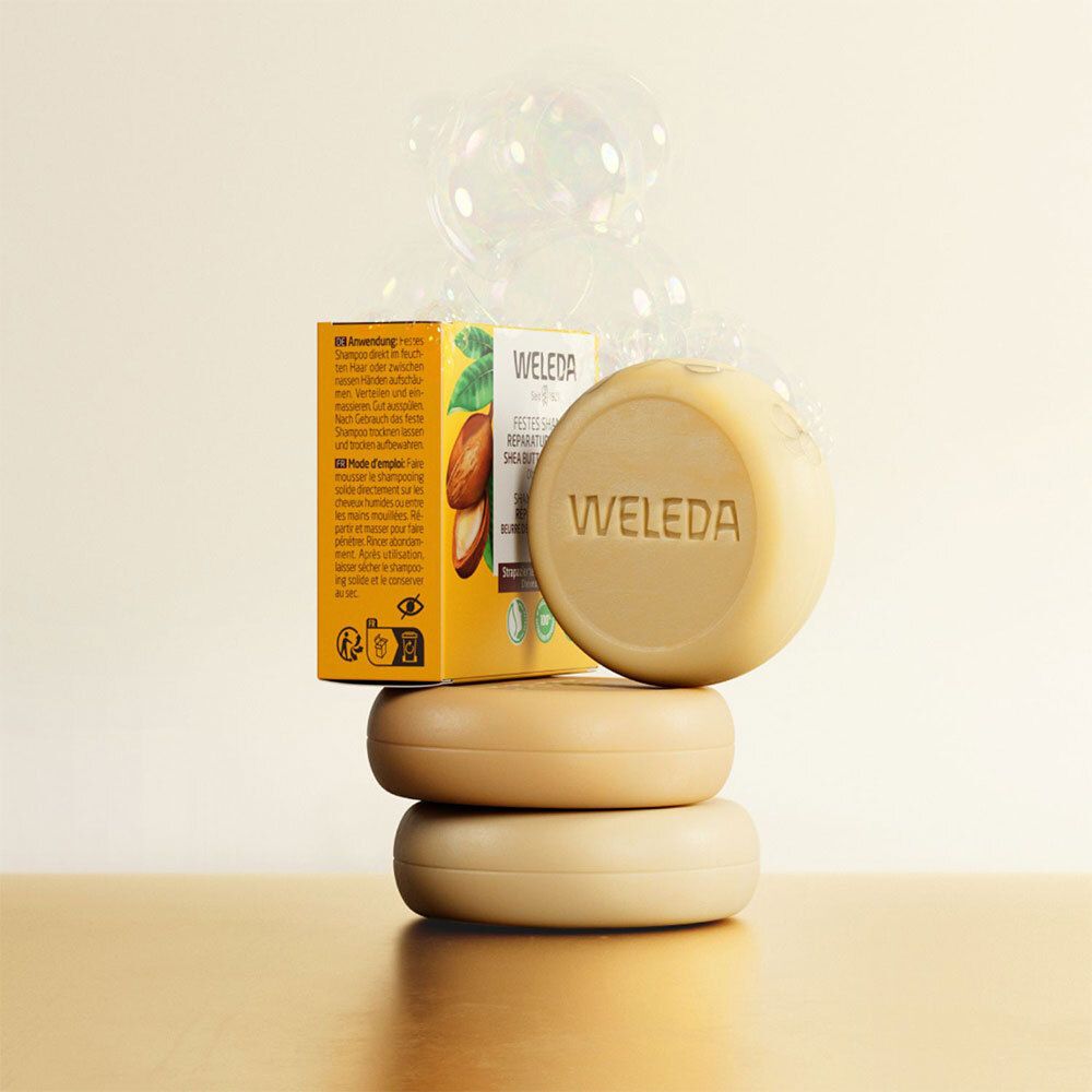 Trois shampooings solides et un emballage. Inscription WELEDA. Savons ronds. Fond jaune avec bulles.