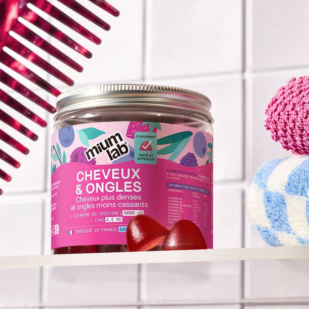 Un pot de Mium Gummies Cheveux & Ongles sur une étagère, avec un peigne et une serviette.