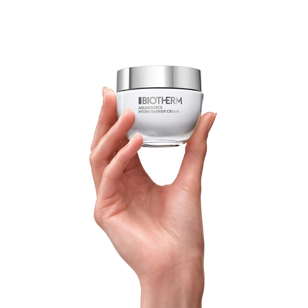 Une main tenant un pot de crème visage Biotherm Aquasource Hydra Barrier.