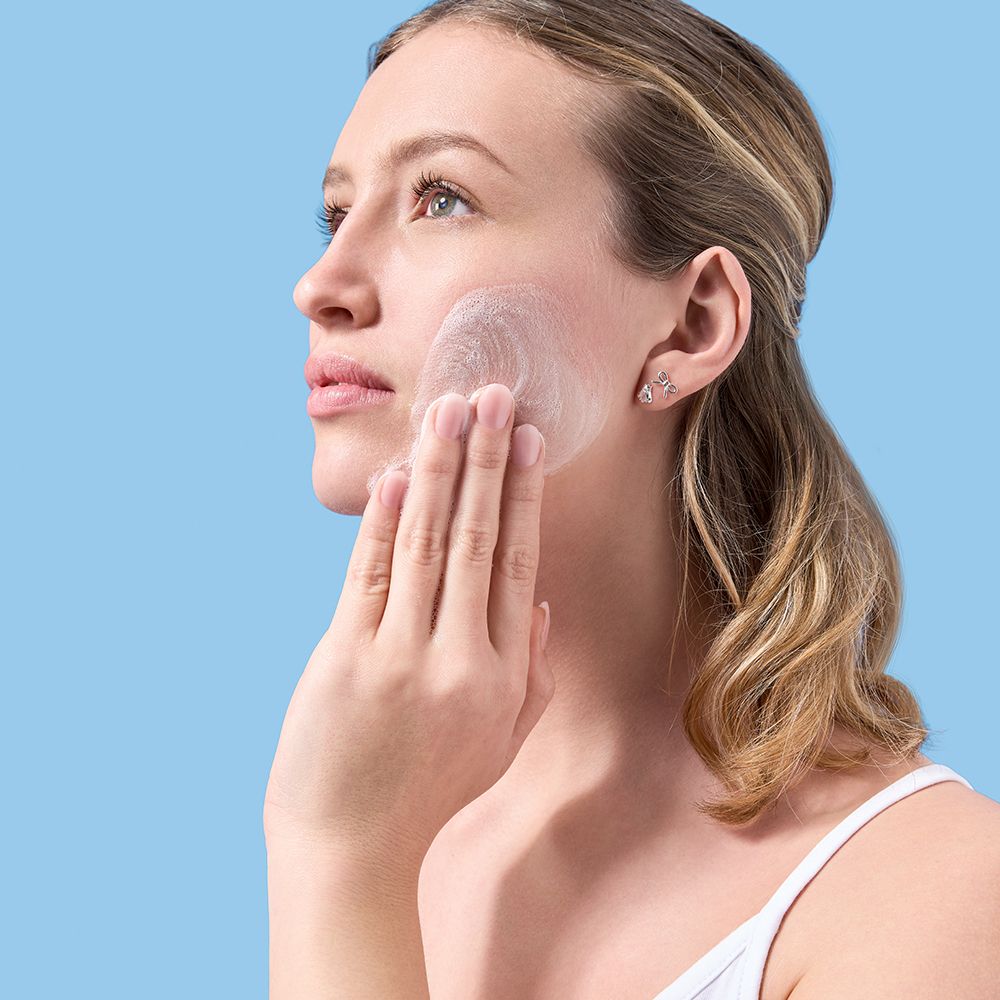 Femme appliquant le produit sur le visage. Texture blanche.