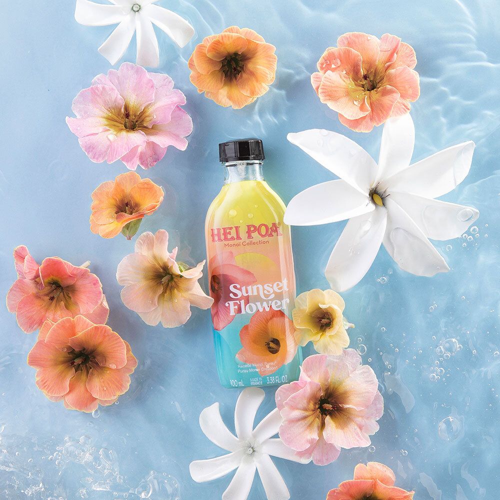 Flacon HEI POA Monoi Sunset Flower dans l'eau, entouré de fleurs. Arrangement floral.