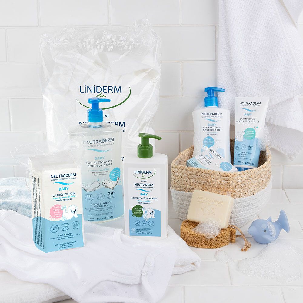 Divers produits avec pompes vertes et bleues. Inscriptions : LINIDERM, NEUTRADERM BABY. Sur une table avec accessoires.