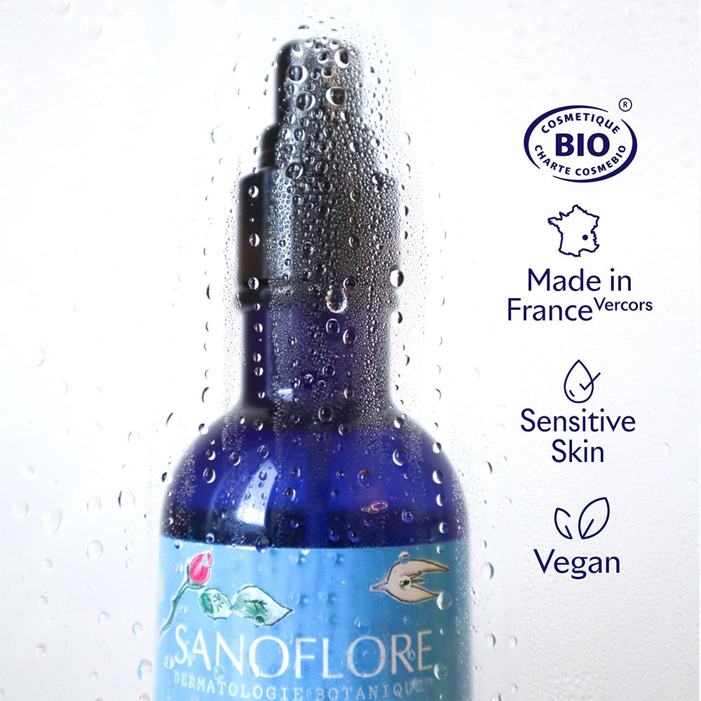 Flacon bleu avec vaporisateur, recouvert de gouttes d'eau. Logos: Bio, Made in France, Sensitive Skin, Vegan.