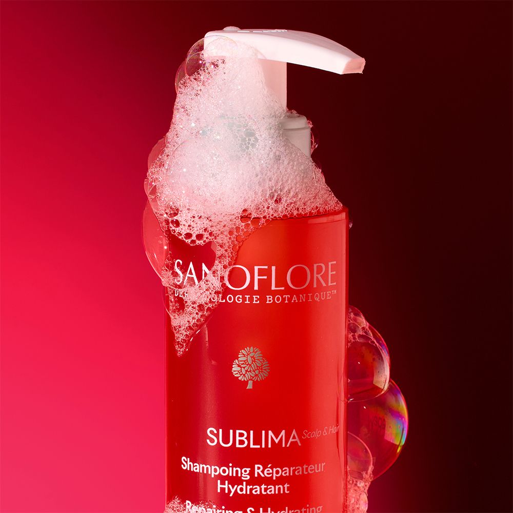 Flacon rouge de shampooing SANOFLORE Sublima avec mousse. Texte : Shampooing réparateur et hydratant.