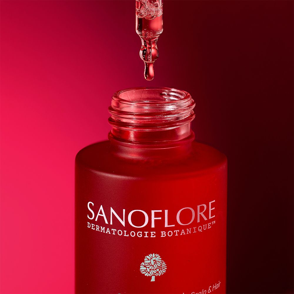 Sérum qui coule d'une pipette dans un flacon rouge. Fond rouge.