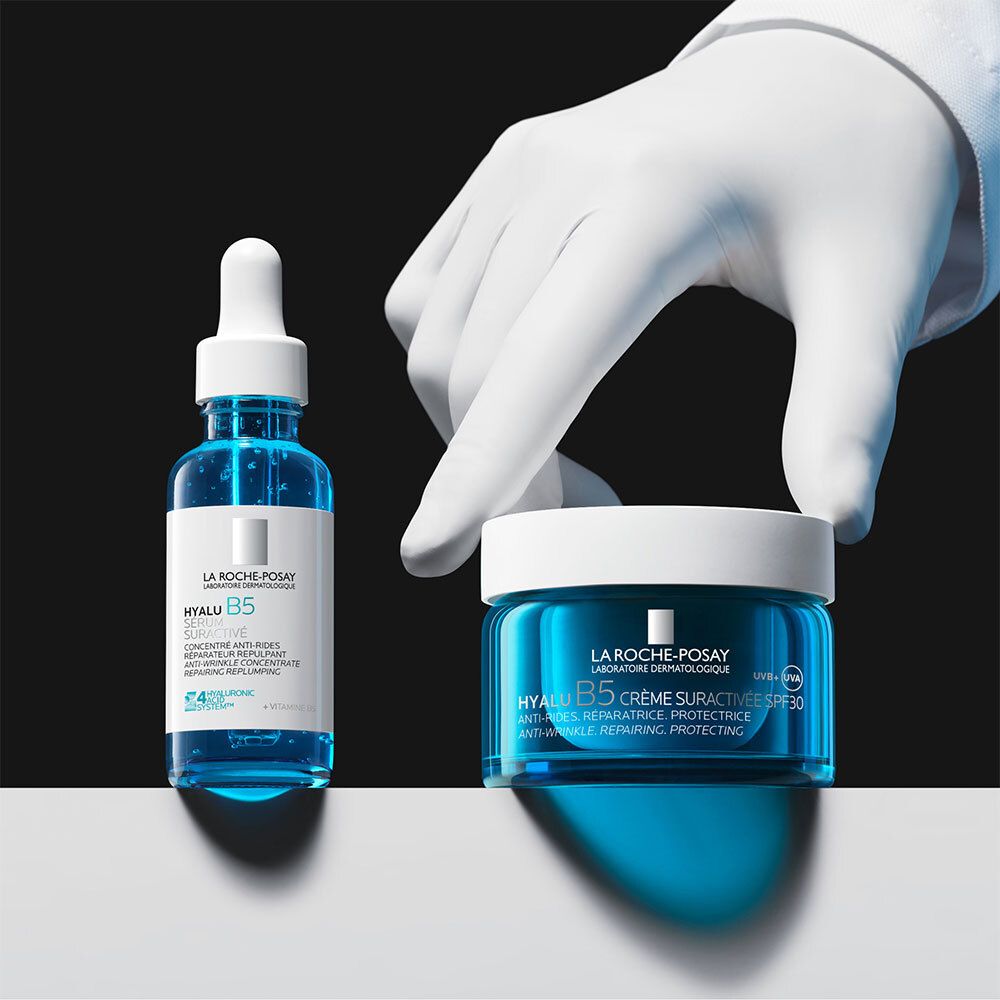 Mains gantées tenant sérum et crème HYALU B5. Texte: HYALU B5, La Roche-Posay.
