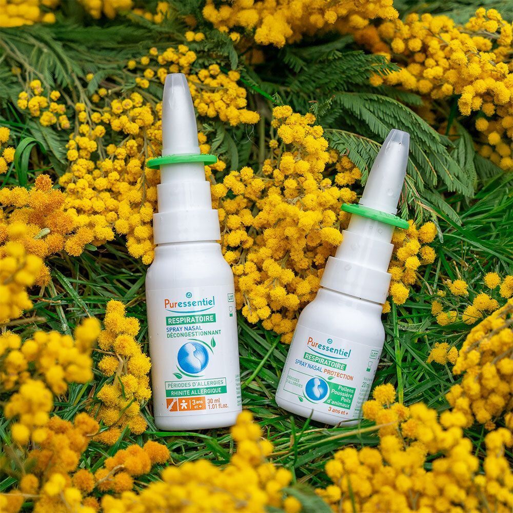 Deux flacons de spray nasal blancs avec anneau vert. Sur fleurs jaunes. Nom du produit visible.