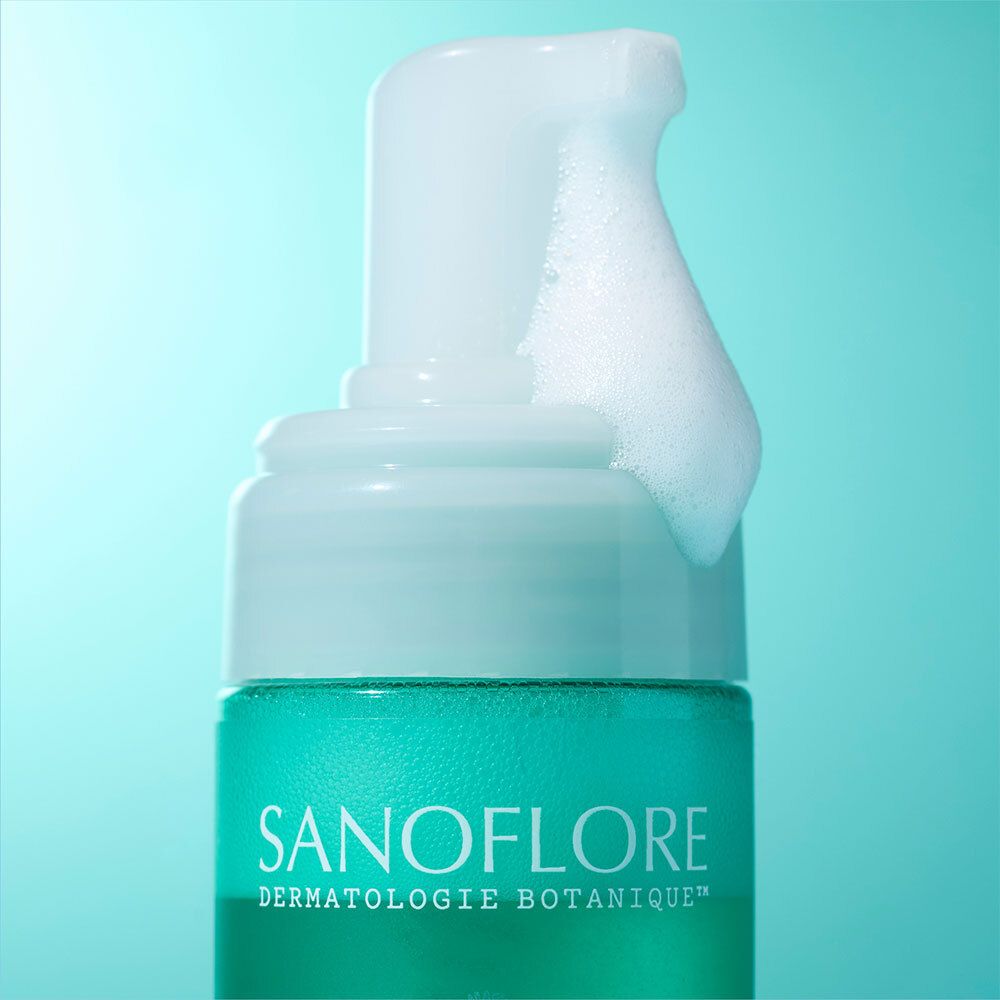 Gros plan sur le flacon vert avec pompe blanche. De la mousse sort du distributeur.
