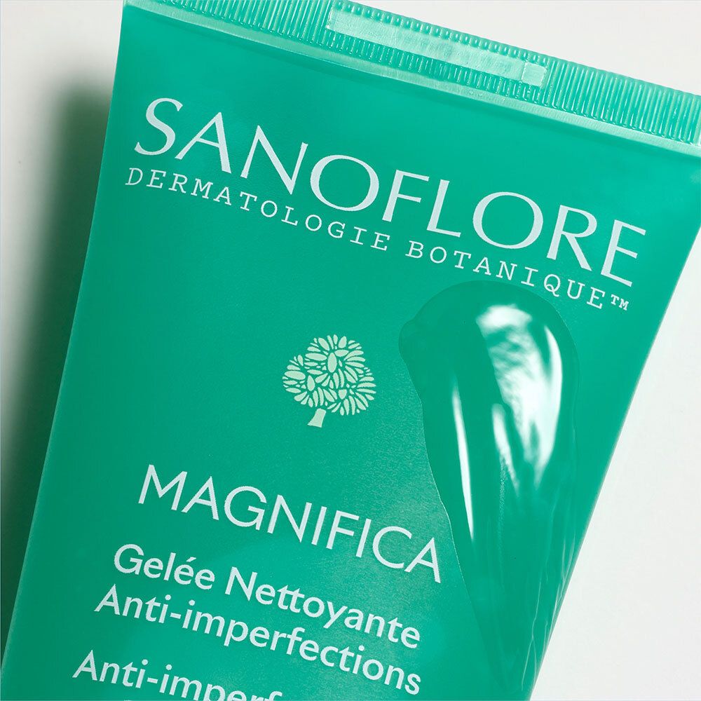 Gros plan du tube. Le nom du produit et la description sont clairement visibles. Fond turquoise.