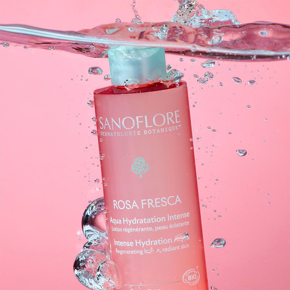 Flasque Sanoflore Rosa Fresca dans l'eau, éclaboussures entourant le flacon.