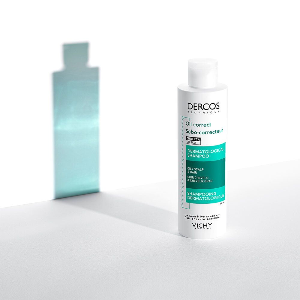 Flacon blanc avec étiquette verte et blanche. Texte: Dercos, Oil correct, Sébo-correcteur, Shampooing dermatologique. Ombre sur fond blanc.