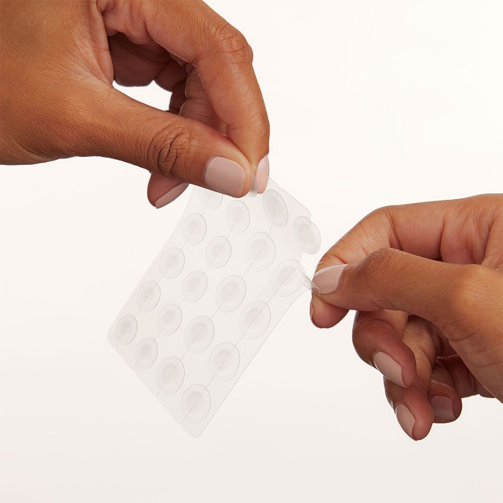 Mains séparant un patch de la plaque plastique transparente.