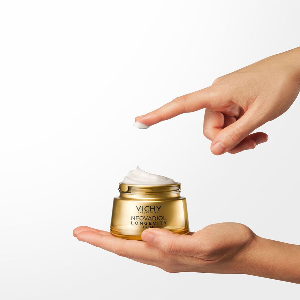 Mains tenant pot et crème. Inscription: VICHY, NEOVADIOL LONGEVITY CREAM.