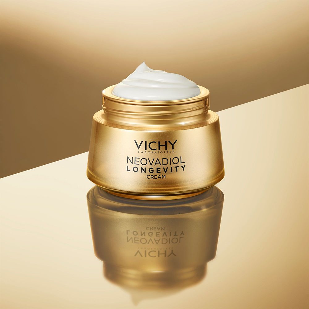 Pot doré avec crème. Nom du produit et marque visibles. Reflet.