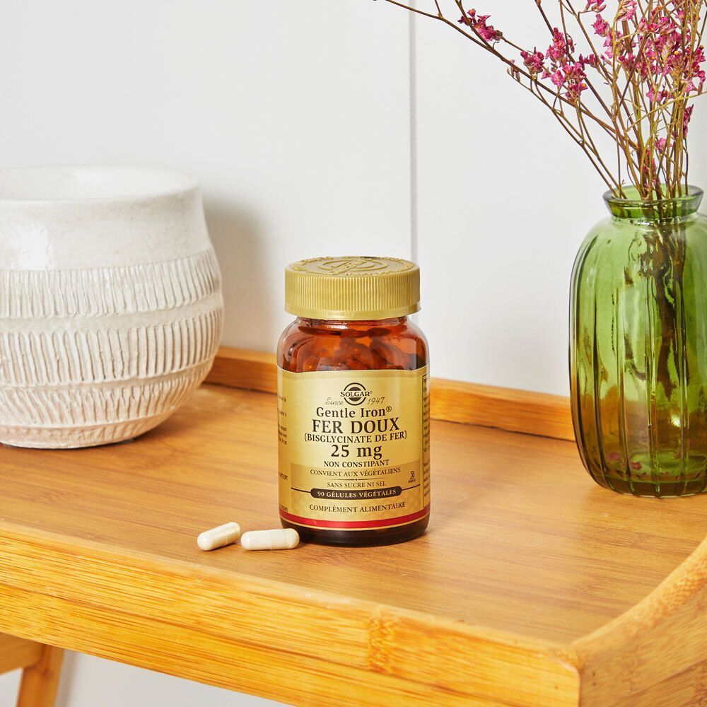 Flacon de Solgar Gentle Iron Fer Doux 25 mg sur une étagère en bois à côté de décorations.