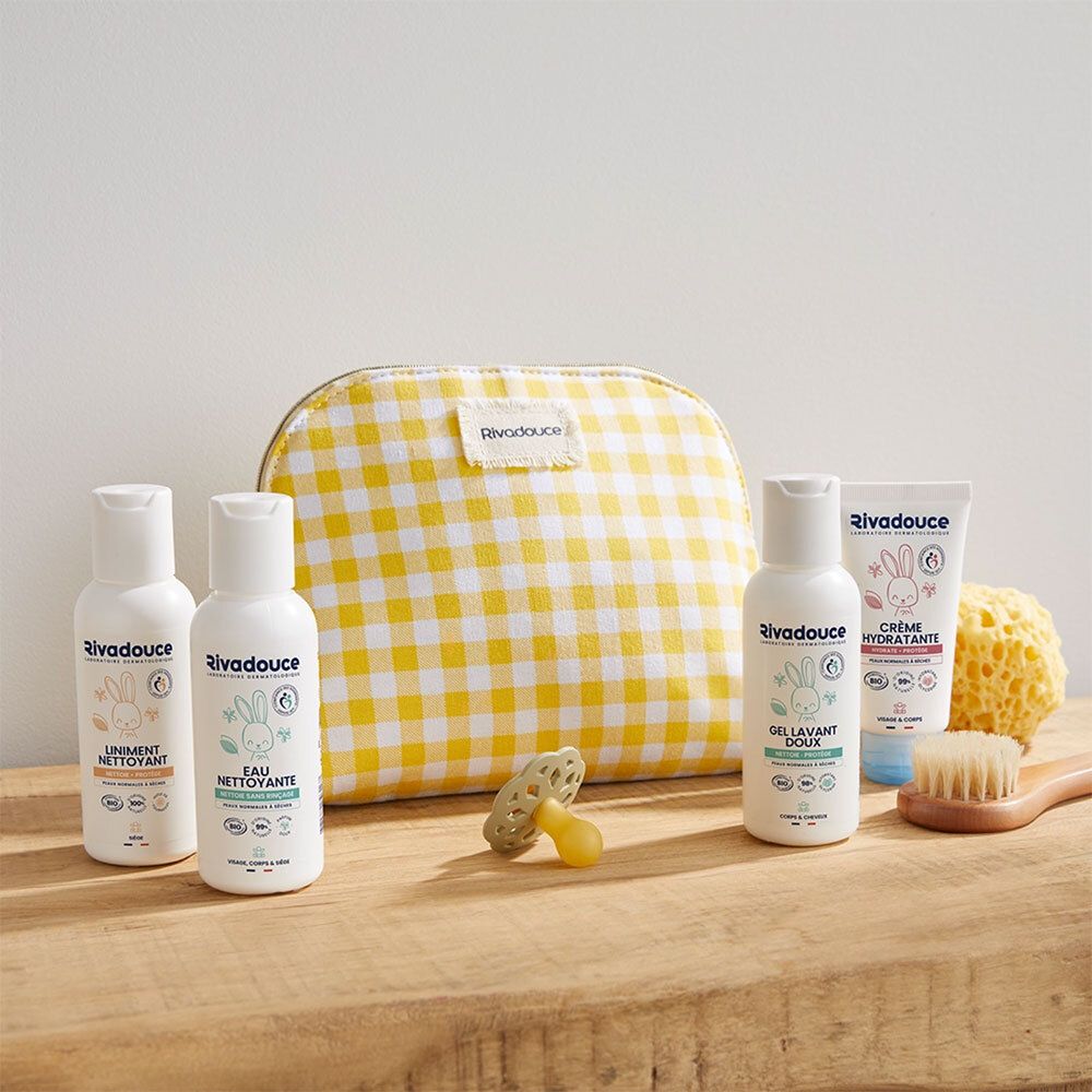Trousse de toilette jaune à carreaux avec produits pour bébé. Contient flacons, tube, sucette, brosse et éponge. Marque : Rivadouce.